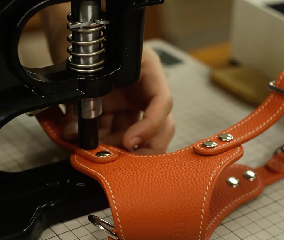 A rivet press setting hardware into an orange harness